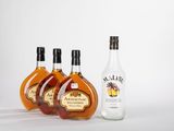 trois bouteilles d'alcool posées les unes à côté des autres sur une surface blanche