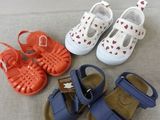 four pairs of baby shoes on a bed
