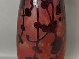 un vase rouge orné de fleurs noires, posé sur une table