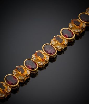 un gros plan sur un bracelet en or orné de pierres rouges et blanches