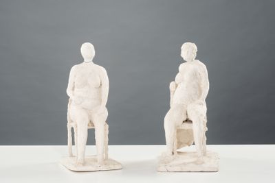 une paire de sculptures blanches représentant un homme et une femme assis sur une chaise