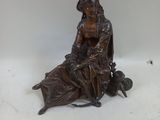 a bronze statue of a woman sitting on a bench