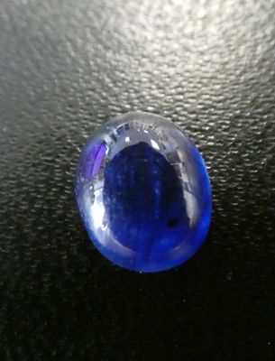 a blue glass ball sitting on a black surface