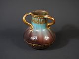 a brown and blue vase sitting on a table
