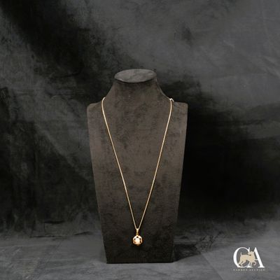 un collier en or posé sur un présentoir à mannequin, sur fond noir