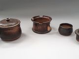 Plusieurs petits pots et tasses sont posés sur une surface blanche.