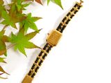 a black and gold bracelet with a gold clasp on it