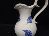 a white pitcher with blue flowers on it on a black background