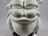 a white ceramic sculpture of a smiling face on a table