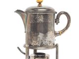 a silver tea pot sitting on top of a stove