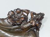 a bronze statue of a woman laying on top of a shoe