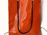 an orange shopping bag with a black handle on a white background
