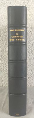 an old black book sitting on top of a table next to a white wall