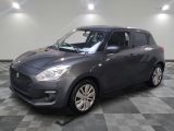 Une Suzuki Swift grise est garée sur un sol carrelé à damier.