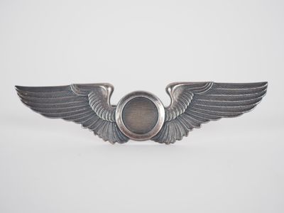 un gros plan d'un insigne orné d'ailes sur fond blanc