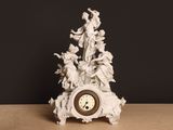 une horloge blanche ornée d'anges, posée sur une table
