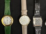 four different colored watches are lined up on a black surface