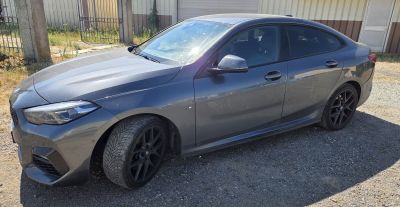 the car is parked on the gravel in front of a building
