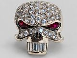 a close up of a skull ring with red eyes and a baguet