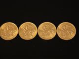 quatre pièces d'or posées côte à côte sur une surface noire