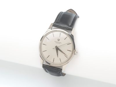 une montre argentée et noire posée sur une surface blanche