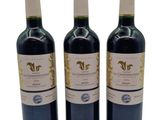 three bottles of red wine sitting next to each other on a white surface