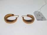 une paire de boucles d'oreilles créoles dorées sur un fond blanc