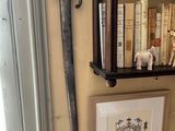 une photo d'un mur sur lequel sont posés des livres et une épée