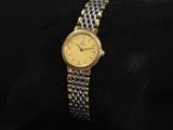 une montre en or et en argent posée sur un coussin noir, sur fond noir