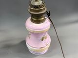 une photo d'une lampe rose et dorée posée sur une table blanche