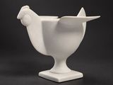 un vase blanc posé sur une table, devant un fond noir