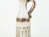 a white vase with a brown handle on a white surface