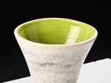 a green and white vase sitting on a white table