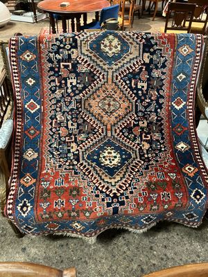 une photo d'un tapis bleu et rouge posé sur une chaise dans une pièce