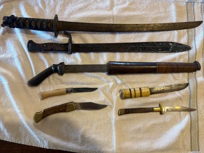 Plusieurs types de couteaux sont disposés sur une serviette posée sur une table