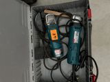 two electric tools sitting in a box on the floor