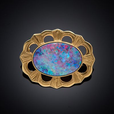 une broche en or ornée d'un oplite bleu en son centre