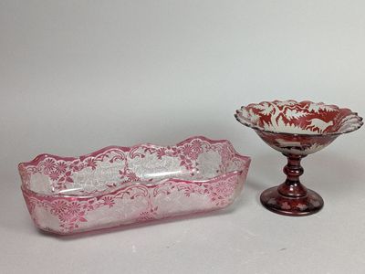 une paire de plats en verre roses et blancs et un saladier posé sur un socle