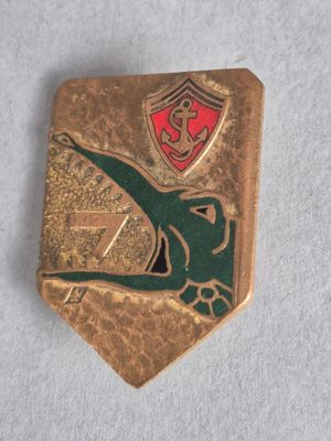 une broche en or ornée d'un emblème vert et rouge