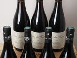 six bottles of wine sit on a wooden crate in front of a white wall