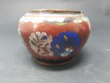 a red vase with blue flowers on it sitting on a table