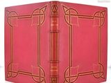 un vieux livre à la couverture rouge posé sur une table blanche