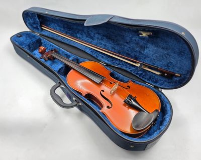 un violon orange repose dans un étui bleu posé sur une surface blanche