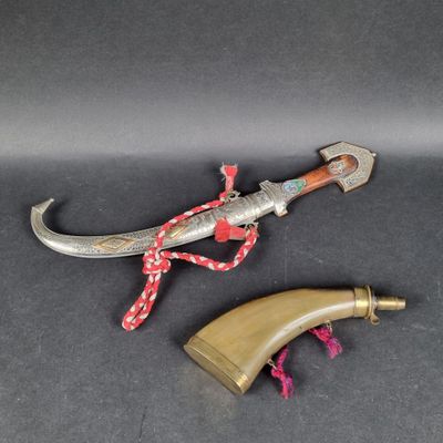 un gros plan d'un couteau posé sur une surface noire, avec une corde rouge