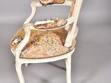 an old chair with a floral upholstered seat and arm rest