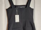 a black dress hanging on a hanger on a white wall