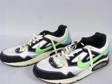 une paire de baskets noires et blanches avec des touches de vert sur un fond blanc