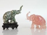two figurines of elephants standing next to each other on a white surface