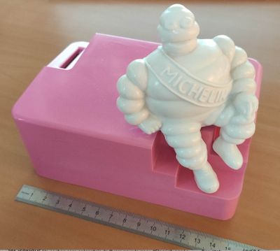 une petite statue blanche représentant un homme assis sur une boîte rose