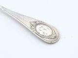 a silver spoon with a clock on it on a white surface